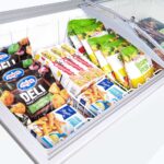 Image of the inside of a 427L medium white display chest freezer with frozen goods, lid open.