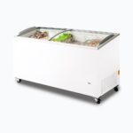 Image of a 555L large white display chest freezer with a curved glass top, right angled view with frozen goods inside.