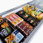 Image of the inside of a 670L large white display chest freezer with colourful frozen goods inside.