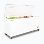 Image of a 675L large white chest freezer with a stainless steel top, left angled view with frozen goods inside.