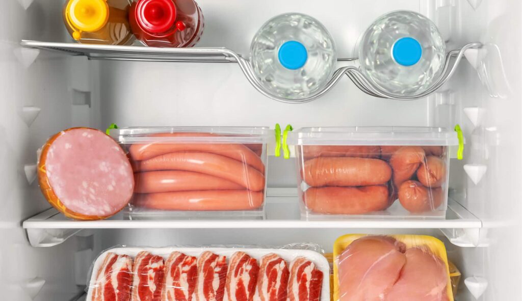 An image of the inside of a fridge where the meat is sitting on the bottom shelf.
